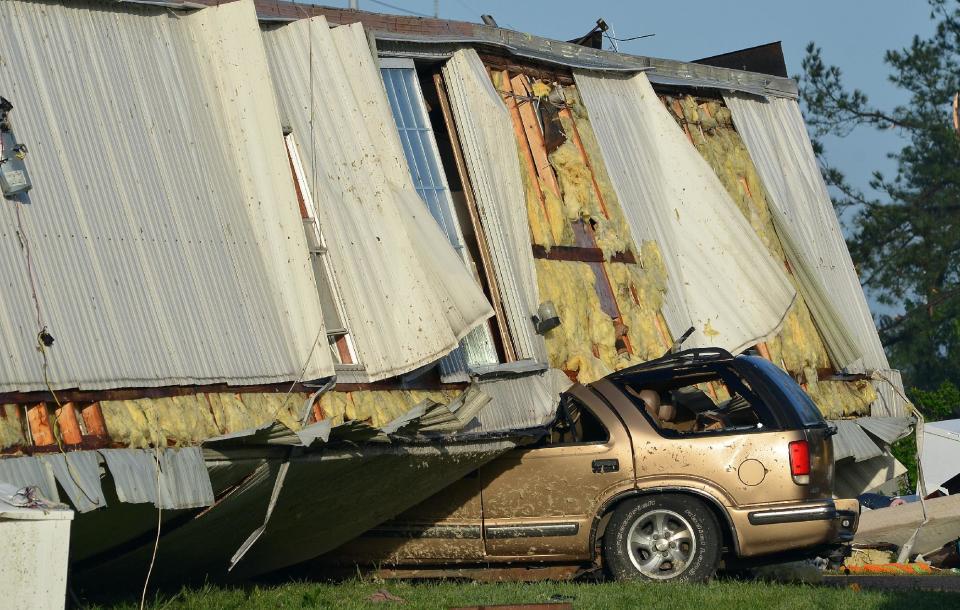 A vehicle sits underneath a mobile home that rolled over on it after being destroyed by a tornado at the Highland Trailer Park in the Greefield area of Pearl, Miss., Tuesday, April 29, 2014. (AP Photo/The Clarion-Ledger, Rick Guy)