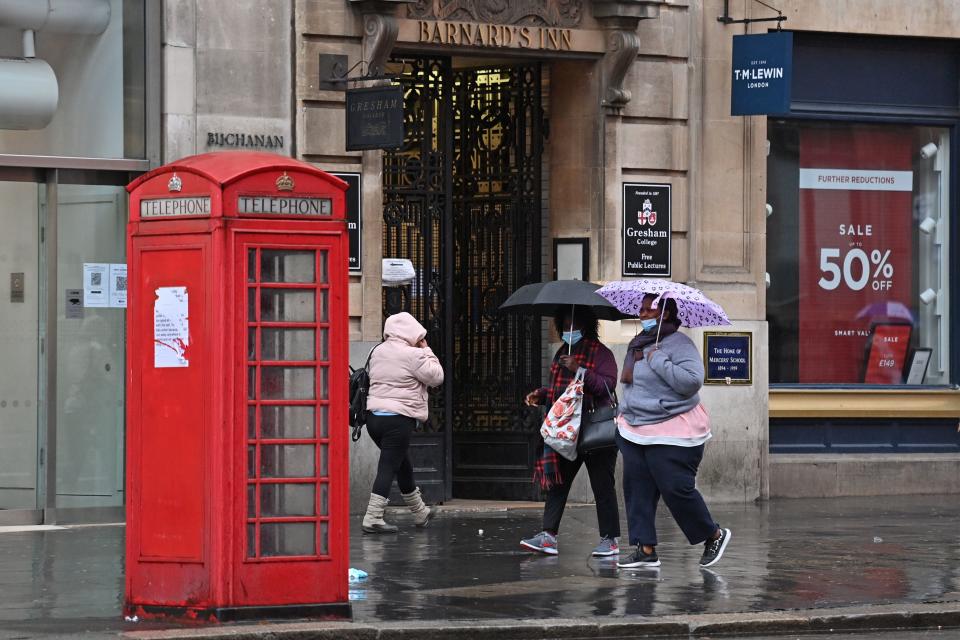 People wearing protective face masks, shelter from the rain under umbrellas as they walks along Holborn in central London on October 21, 2020, as the government considers further lockdown measures to combat the rise in novel coronavirus COVID-19 cases. - Britain has suffered Europe's worst death toll from coronavirus, with nearly 44,000 deaths within 28 days of a positive test result. After a summer lull, cases are rising again as in other parts of the continent -- and so are deaths, with 241 reported on Tuesday alone. (Photo by JUSTIN TALLIS / AFP) (Photo by JUSTIN TALLIS/AFP via Getty Images)