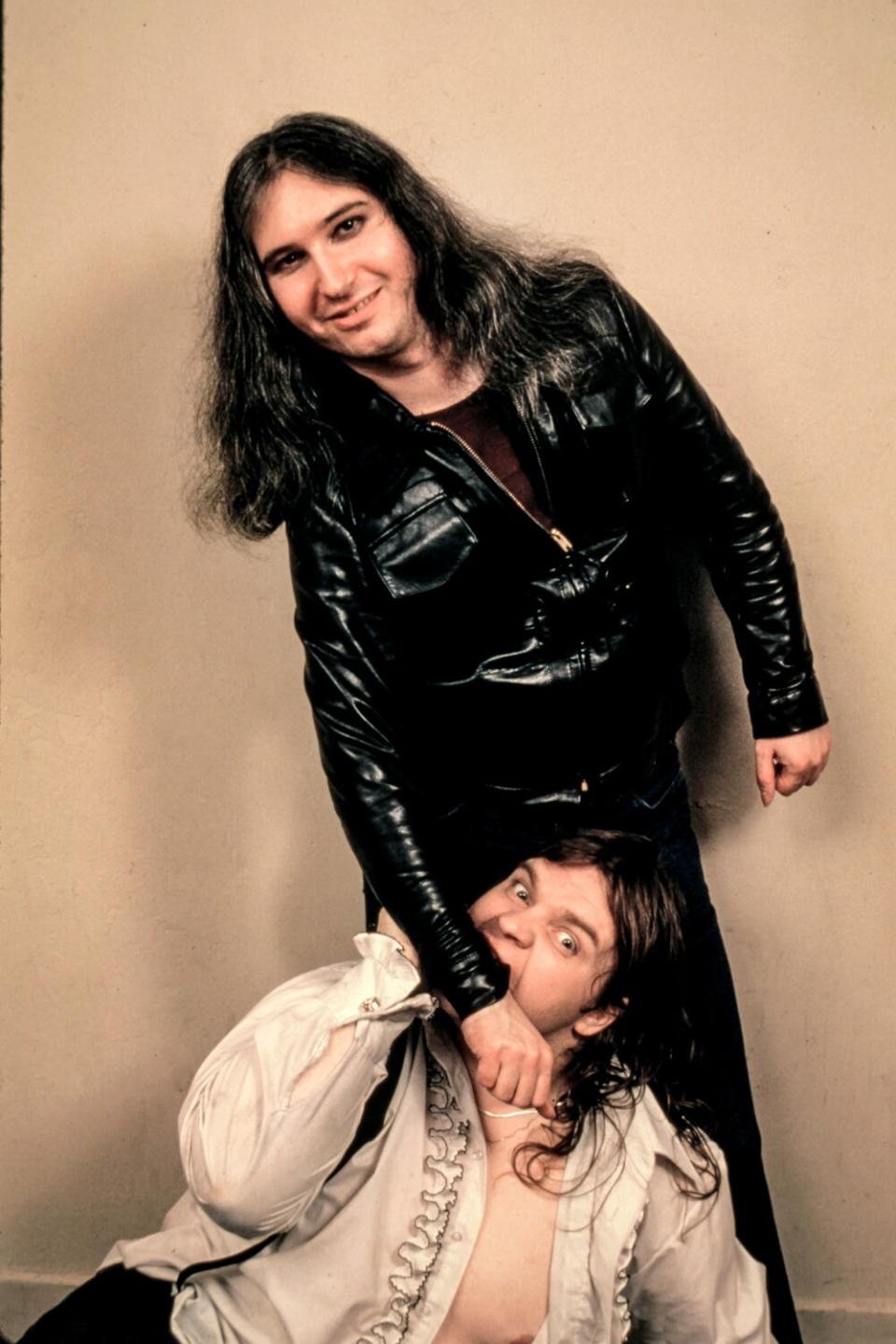 Meat Loaf pretends to bite the arm of Jim Steinman.