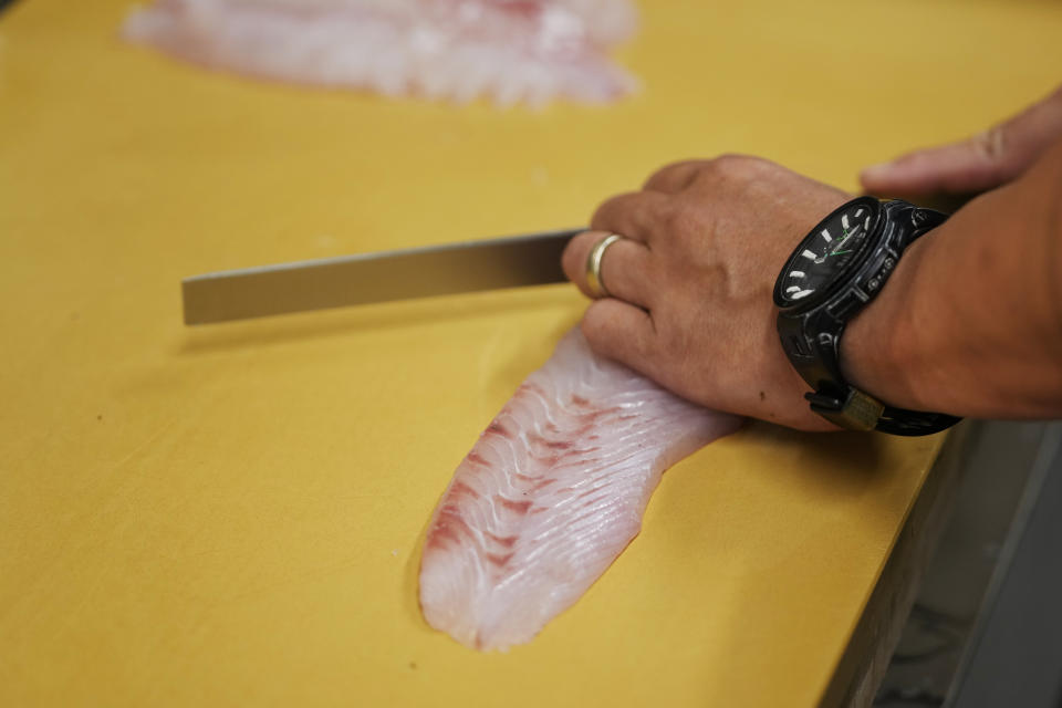 Katsumasa Okawa, owner of a fish store and a restaurant, cuts flounder meat as he prepares at his restaurant in Iwaki, northeastern Japan, Thursday, July 13, 2023. Okawa said those tanks containing contaminated water at the damaged Fukushima nuclear power plant bothers him more than the treated water release into the sea. He wants to have them removed as soon as possible, especially after seeing "immense" tanks occupying much of the plant complex during his visit a few years ago. (AP Photo/Hiro Komae)