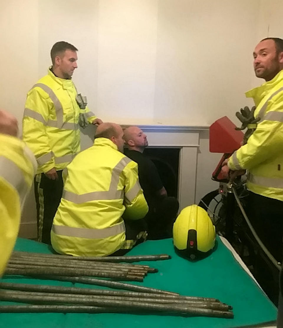 These incredible pictures show the moment rescuers freed a stricken cat who had been stuck up a chimney - for SIX days. See SWNS story SWPLchimeny. The stricken feline was discovered after Jenny and David Williams heard a mysterious scratching. They heard a meow and realised a cat was stuck in a disused chimney behind the wall of their business in Ilfracombe, Devon. The pair, who run AD Williams funeral directors, called in rescuers from North Devon Animal Ambulance and Metro Rod who set about launching an impressive rescue.