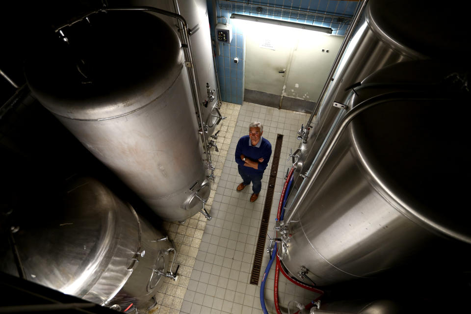 In this photo taken Friday, May 1, 2020 brewer Karlmann Detter poses between brewery tanks in his 120 year old family brewery in Altoetting, Germany. The 'Graminger Weissbraeu' brewery, which has been in the same family for a century, is preparing to welcome guests back to its restaurant for the first time in two months — with new rules and fears for the future. (AP Photo/Matthias Schrader)