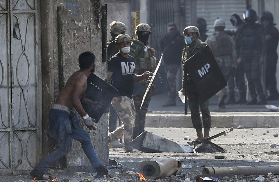 A protester prepares to throw a stone during clashes between Iraqi security forces and anti-government protesters in downtown Baghdad, Iraq, Monday, Nov. 11, 2019. (AP Photo/Hadi Mizban)