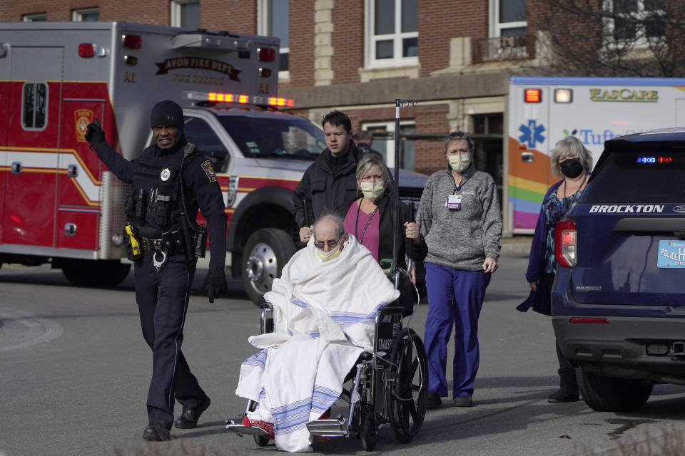 A patient, below, is evacuated from Signature Healthcare Brockton Hospital, Tuesday, Feb. 7, 2023, in Brockton, Mass. A fire at the hospital's electrical transformer forced an undetermined number of evacuations Tuesday morning and power was shut off to the building for safety reasons, officials said. (AP Photo/Steven Senne)