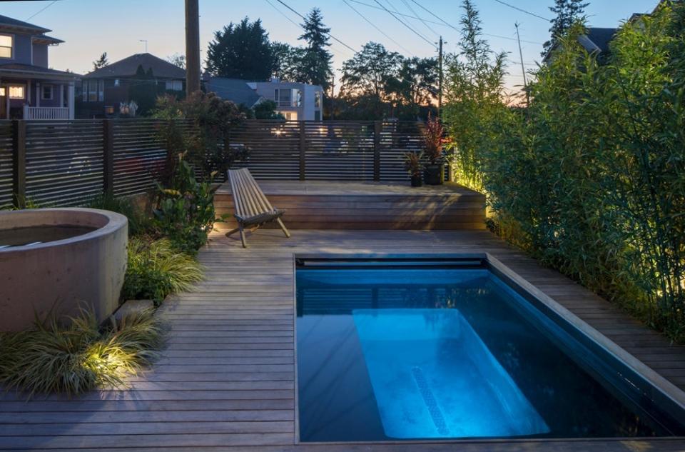 A Zen garden, planted with ferns, grasses, and leafy, sculptural flowers, leads to the spa area, where the flooring transitions to a patio of black flagstone in organic shapes and ipe decking around the circular plunge pool and rectangular hot tub. Photo by Lara Swimmer