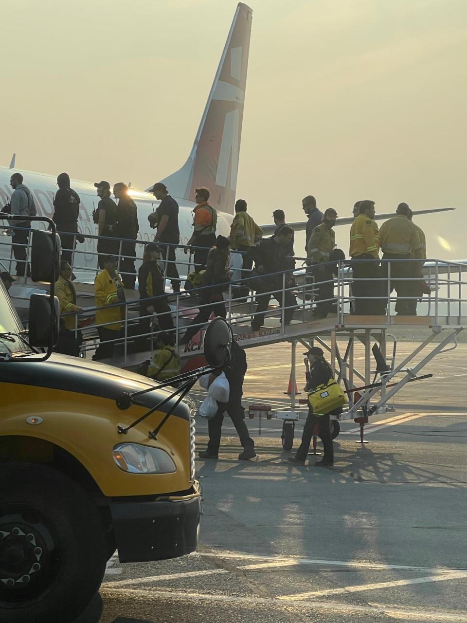 Firefighters board a plane in Yellowknife on Wednesday evening.  (Joanne Stassen/CBC - image credit)