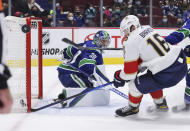 Vancouver Canucks goalie Spencer Martin (30) watches as the puck deflects wide of the goal off the stick of Florida Panthers' Aleksander Barkov (16) during overtime in an NHL hockey game Friday, Jan. 21, 2022, in Vancouver, British Columbia. (Darryl Dyck/The Canadian Press via AP)