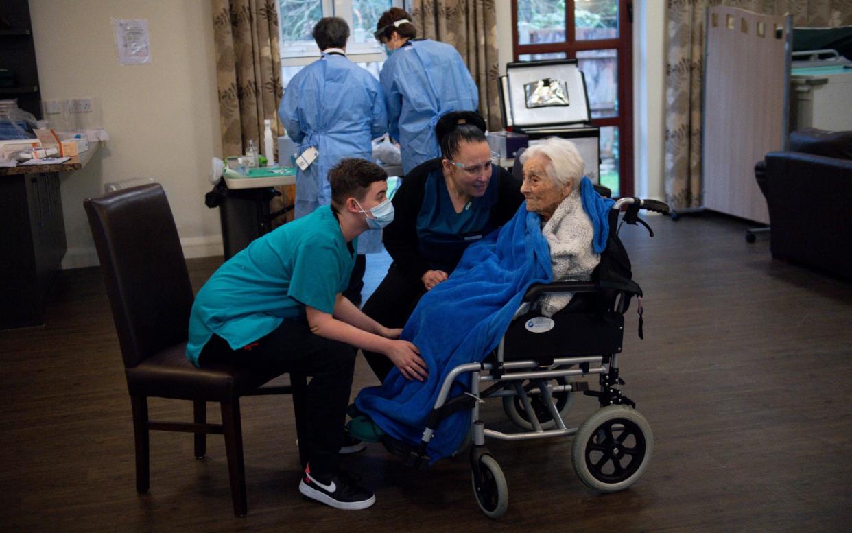 Staff talk to care home resident Vera Levick, 106, before she receives her coronavirus vaccine at Andrew Cohen House in Birmingham - Jacob King/PA