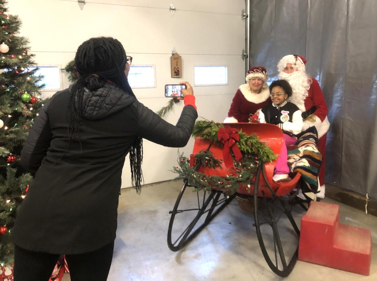 Lydzaida Montanez grabs a snapshot of daughter Candace, 10, and Mr. and Mrs. Claus during a Manchester Fire Department open house and kickoff to the holiday season Saturday.
