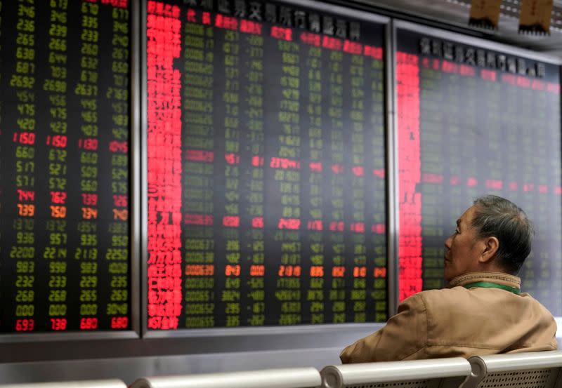 FILE PHOTO: An investor watches a board showing stock information at a brokerage office in Beijing