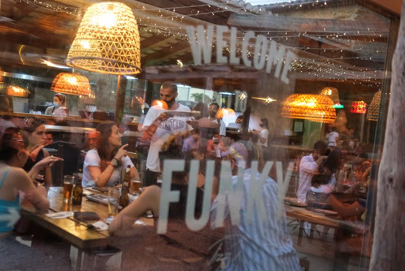 An employee carrie a pizza for clients, who ordered it through the "Funky Pay" app, at Funky Pizza restaurant, where the app replaces waiters, in Palafrugell