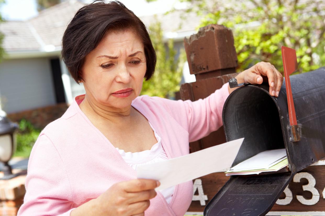 worried senior Hispanic woman checking mailbox