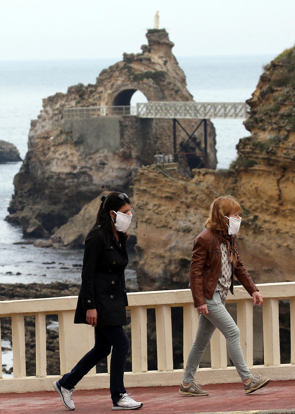 People wearing face masks walk during a nationwide confinement to counter the COVID-19, in Biarritz, southwestern France, Saturday April 11, 2020. The new coronavirus causes mild or moderate symptoms for most people, but for some, especially older adults and people with existing health problems, it can cause more severe illness or death. (AP Photo/Bob Edme)