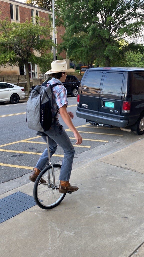 A University of Tennessee at Knoxville student wearing a cowboy hat while riding a unicycle to class. He rode past reporter Keenan Thomas during the parking versus walking challenge.