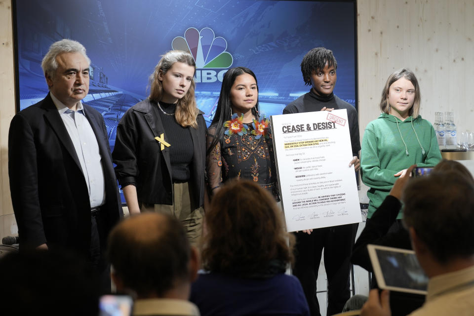 Climate activists Greta Thunberg of Sweden, Vanessa Nakate of Uganda, Helena Gualinga of Ecuador and Luisa Neubauer of Germany, from right, stand together with a notice to Fossil Fuel CEOs, beside Fatih Birol, Head of the International Energy Agency, left, after a press conference at the World Economic Forum in Davos, Switzerland Thursday, Jan. 19, 2023. The annual meeting of the World Economic Forum is taking place in Davos from Jan. 16 until Jan. 20, 2023. (AP Photo/Markus Schreiber)