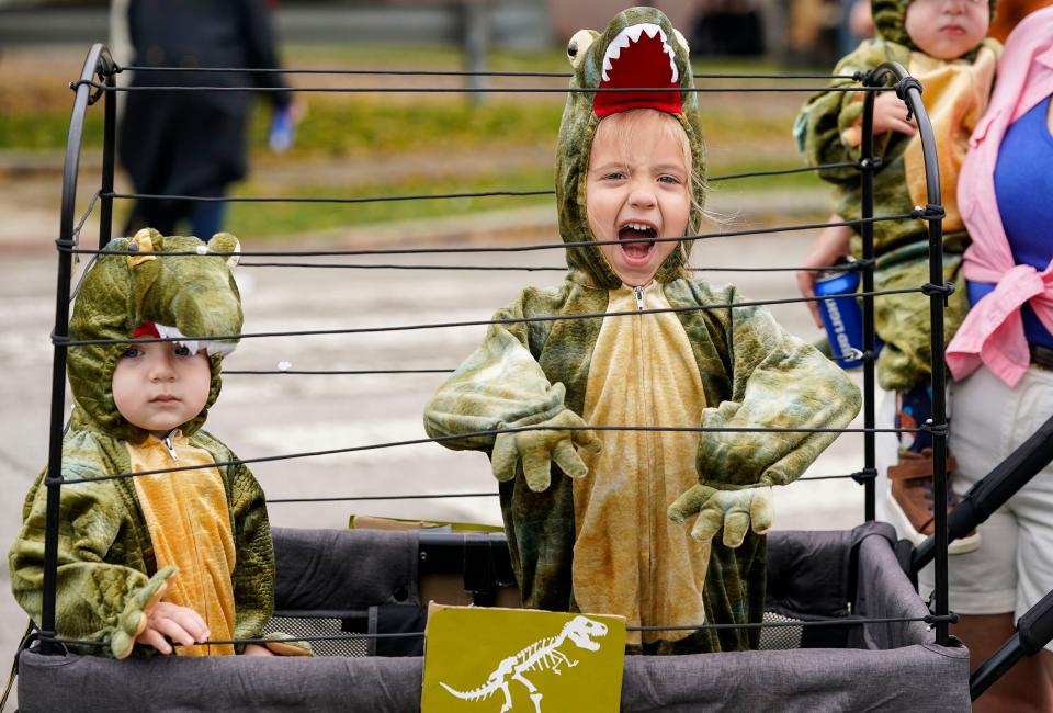 Mirian Buchanan, 3, rides around in a stooler dresses as velociraptors with her younger sibling during the Historic Halloween Festival on Saturday, Oct. 30, 2021 at Irvinginton, in Indianapolis. 