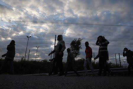 Migrants are seen in silhouette as they make their way along near a fence near train tracks as they attempt to access the Channel Tunnel in Frethun, near Calais, France, July 29, 2015. REUTERS/Pascal Rossignol