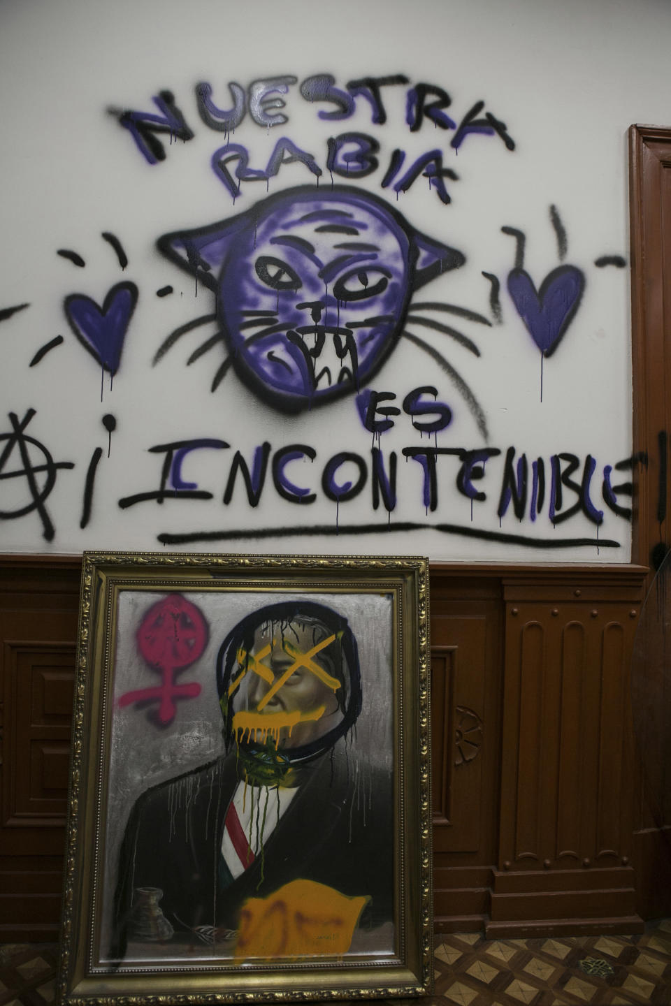 Un cuadro con la imagen desfigurada del expresidente mexicano Benito Juárez, bajo una pintada con la frase "Nuestra rabia es incontenible", realizada por activistas en el interior de la sede de la Comisión Nacional de los Derechos Humanos, que está ocupada desde hace casi tres meses y sirve de refugio para víctimas de violencia de genero, en la Ciudad de México, el 17 de noviembre de 2020. Las activistas ocupan el inmueble para pedir justicia para las víctimas de abusos sexuales, feminicidio y otros tipos de violencia de género, y dan refugio a algunas mujeres y a sus hijos luego de que el gobierno no resolvió o investigó ataques sexuales a las hijas de sus invitadas. (AP Foto/Ginnette Riquelme)