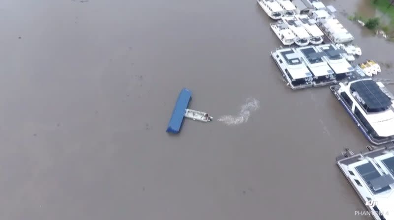 Boat pushes a container away from moving towards houseboats in Wisemans Ferry