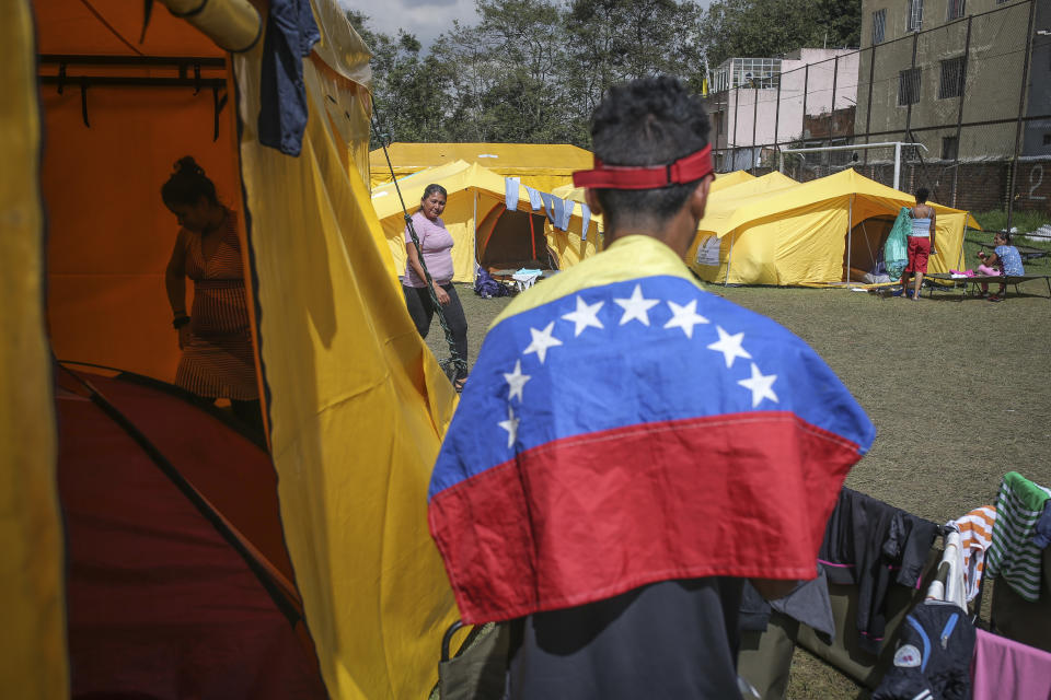 Venezuelan migrants live in a camp built by the municipal government in Bogota, Colombia, Wednesday, Nov. 21, 2018. The camp was built to accommodate migrants who had previously been living in tents made of plastic sheets and scrap materials outside the city's bus terminal. (AP Photo/Ivan Valencia)