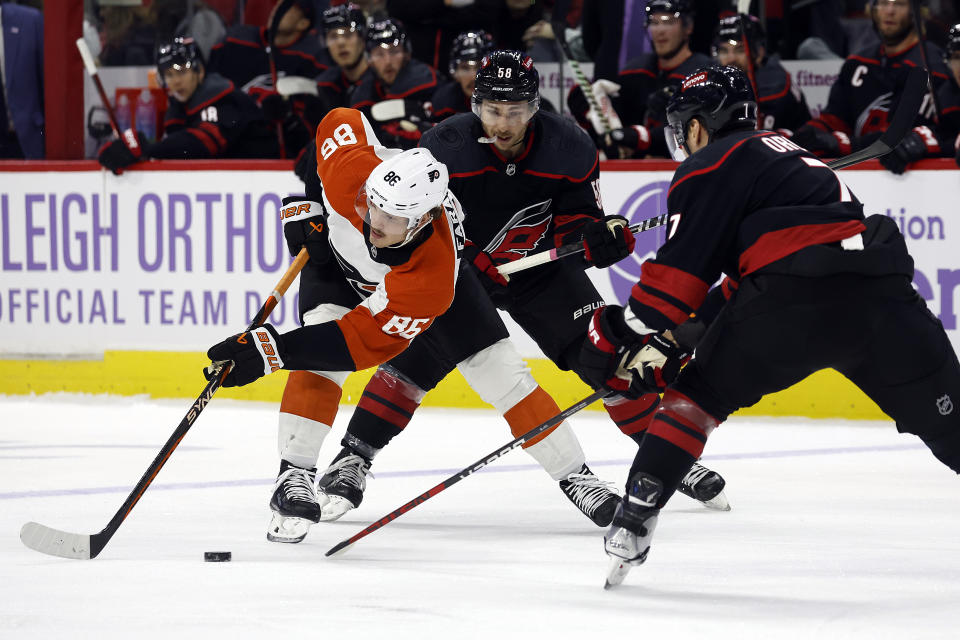 Philadelphia Flyers' Joel Farabee (86) tries to maintain control of the puck with Carolina Hurricanes' Michael Bunting (58) and Dmitry Orlov (7) nearby during the first period of an NHL hockey game in Raleigh, N.C., Wednesday, Nov. 15, 2023. (AP Photo/Karl B DeBlaker)