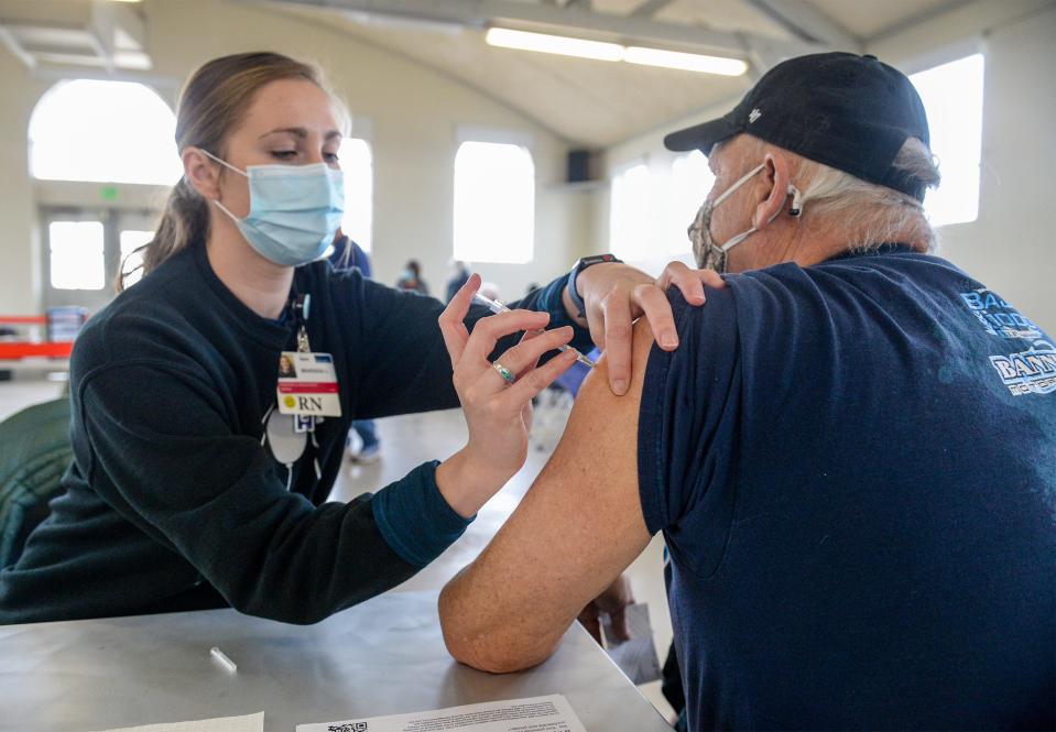 Benefis nurse Marissa Lencioni administers the Pfizer COVID-19 vaccine to Great Falls resident Mick Cabbage during a vaccination clinic Monday morning in the Family Living Center building at Montana ExpoPark.