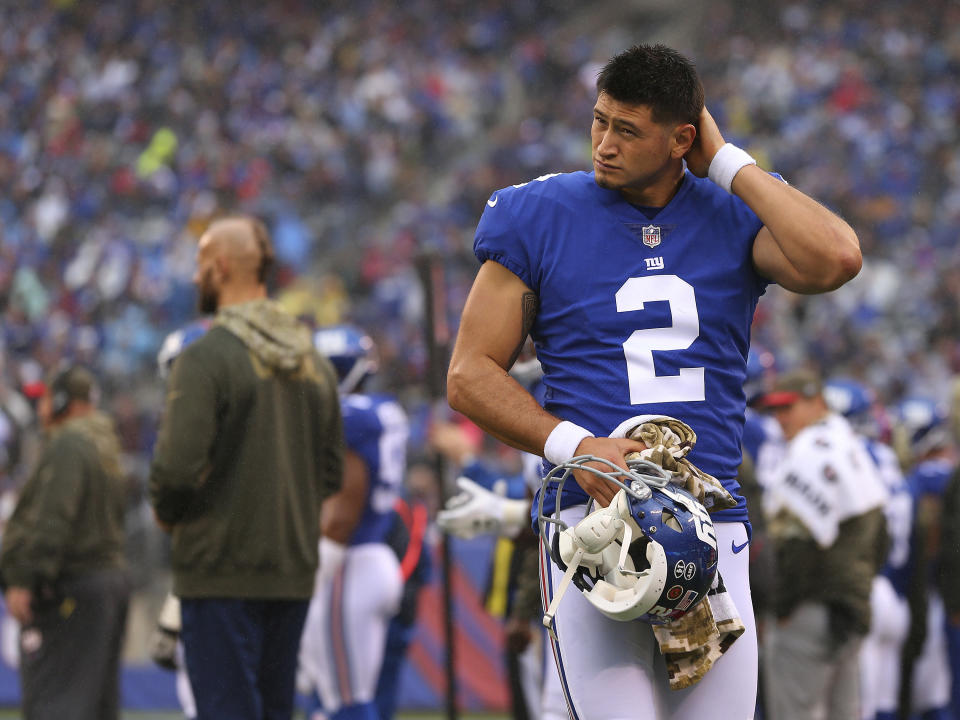 New York Giants' Aldrick Rosas in uniform and holding his helmet on the sidelines of a football game.