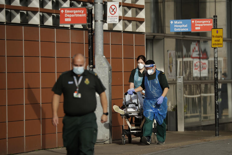 A patient is wheeled on a trolley after arriving in an ambulance outside the Royal London Hospital in east London, Thursday, Feb. 4, 2021. The U.K. is under an indefinite national lockdown to curb the spread of the new variant, with nonessential shops, gyms and hairdressers closed, most people working from home and schools largely offering remote learning. (AP Photo/Matt Dunham)