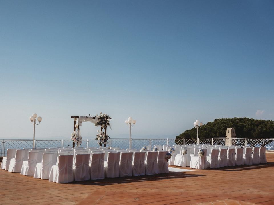 A wedding ceremony on a patio in front of the ocean.