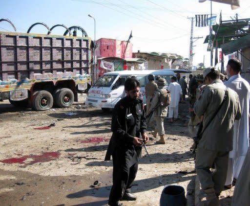 Pakistani security officials examine the site of a suicide bombing in Khar, the main town of Bajaur district. A teenage suicide bomber targeted police in a bustling Pakistan town square on Friday, killing at least 24 people and wounding dozens in the tribal area near the Afghan border, officials said