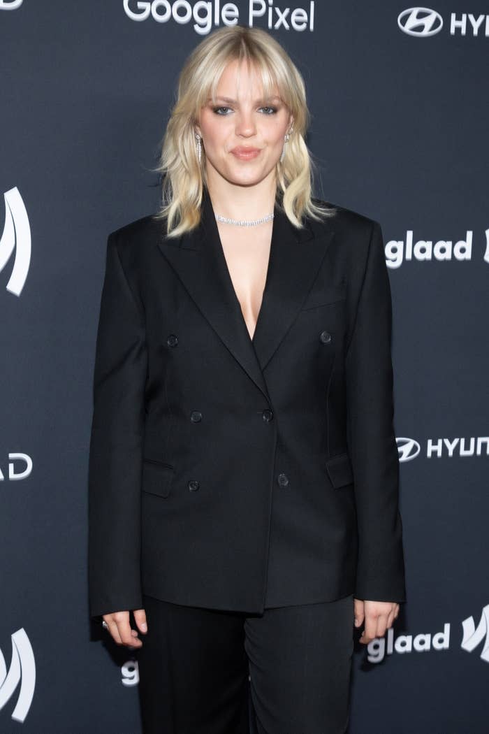 Renee in elegant black suit stands on the GLAAD event backdrop