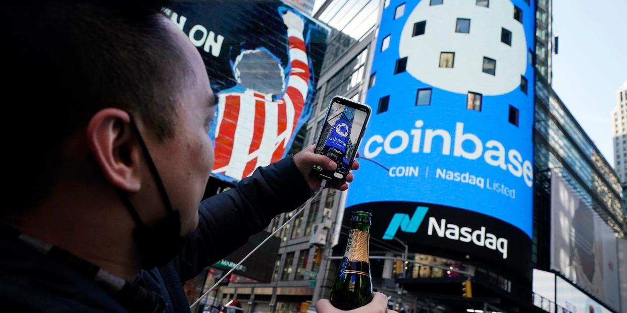 Coinbase employee Daniel Huynh holds a celebratory bottle of champagne as he photographs outside the Nasdaq MarketSite, in New York's Times Square, Wednesday, April 14, 2021.