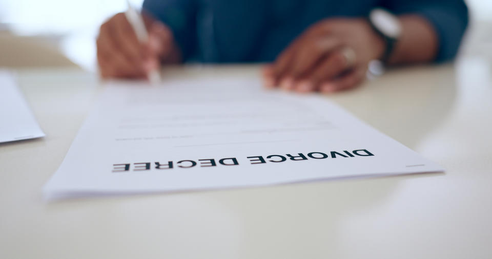 Hands signing a divorce decree document, emphasizing legal dissolution of marriage