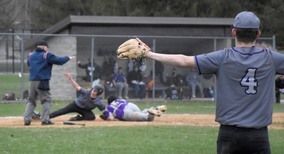 Little Falls Mountie Chase Regan (4) gives a safe sign, as does the plate umpire, after Mountie Rikki Smith slid around the tag of West Canada Valley catcher Dylan Dayton and scored the go-ahead run in the seventh inning of Monday's game in Newport.