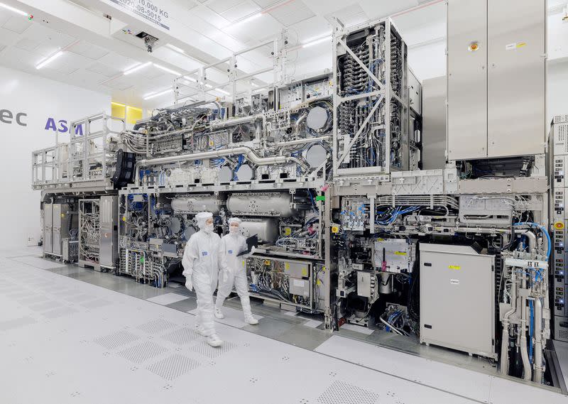 ASML engineers walk past a High NA EUV tool at ASML’s headquarters in Veldhoven