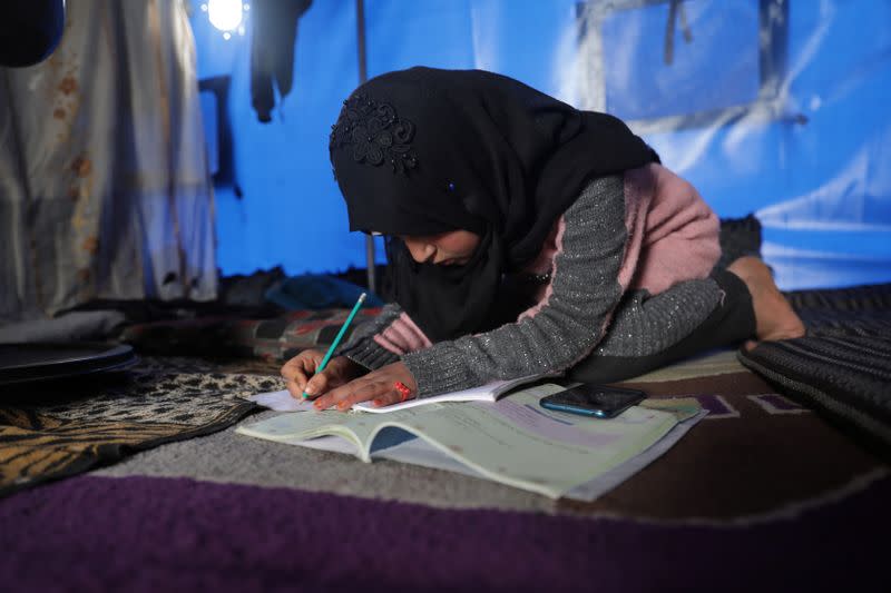 Internally displaced girl, Alaa Hussein Hadaja,10, studies inside her tent in Atmeh camp