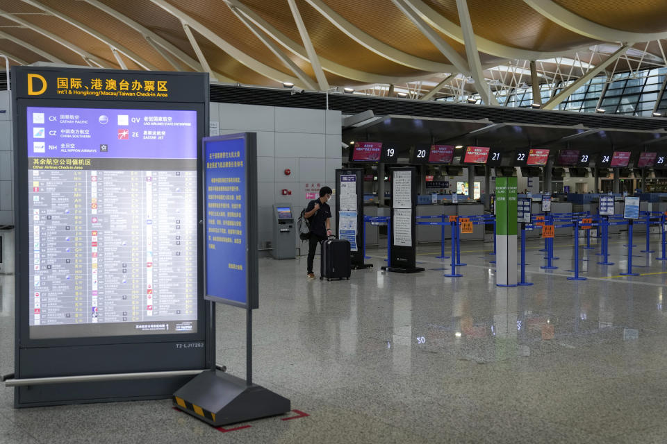 A passenger looks at information notice of a flight after all flights were canceled at Pudong International Airport in Shanghai, China, Sunday, July 25, 2021. Airline flights were canceled in eastern China and cargo ships were ordered out of the area Saturday as Typhoon In-fa churned toward the mainland after dumping rain on Taiwan. (AP Photo/Andy Wong)