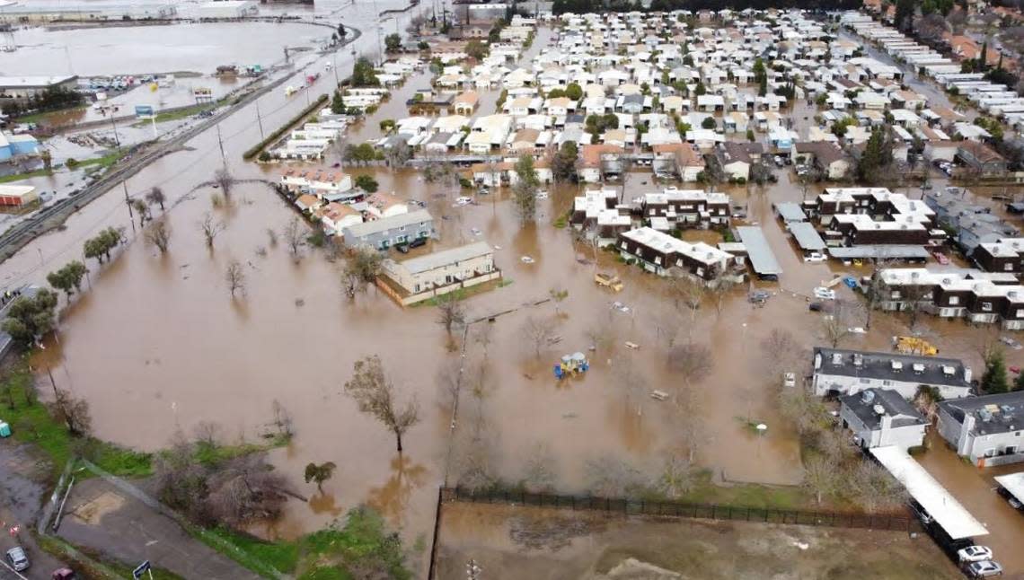 Water surrounds a neighborhood at West 16th Street and Highway 59 in western Merced after Bear Creek overflowed its banks during a Jan. 10, 2023 storm. In this view looking north, the Riveria Holiday Mobile Estates senior mobile home park is also inundated.