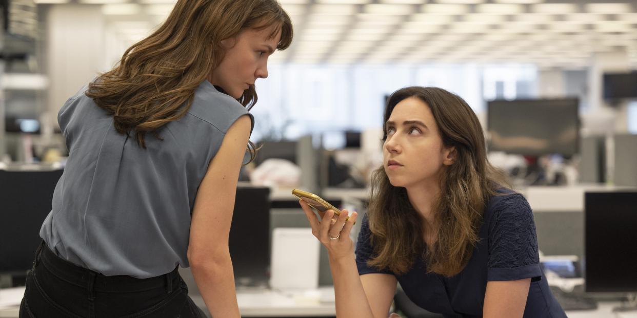 Carey Mulligan and Zoe Kazan sitting on a desk listening to a phone