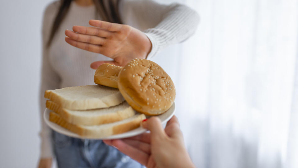 Young woman on gluten free diet is saying no thanks to toast. A woman on a gluten free diet is saying no thanks to toast. Woman refusing to eat white bread