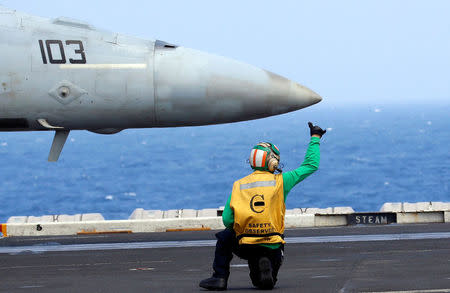 A flight deck crew gives a hand signal to the pilot of a U.S. Navy F18 fighter jet on aircraft carrier USS Carl Vinson. REUTERS/Erik De Castro