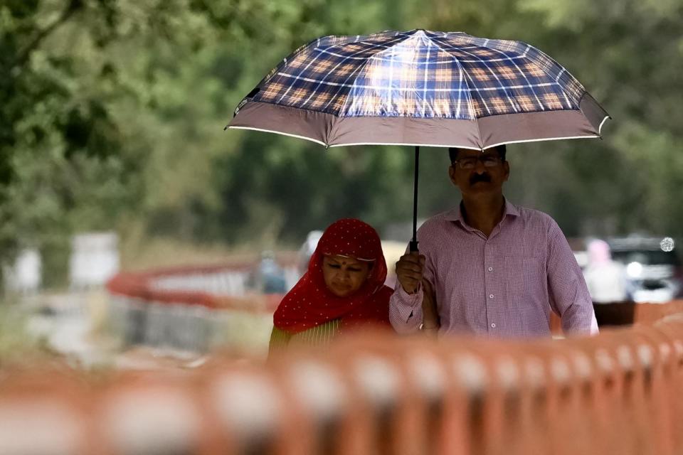 PHOTO: People walk under a umbrella on a hot summer afternoon in New Delhi on May 29, 2024, amid ongoing heatwave.  (Arun Sankar/AFP via Getty Images)