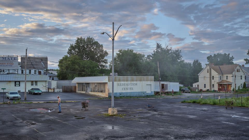 In “An Eclipse of Moths,” from 2018-2019, Crewdson favored wide shots of a melancholic post-industrial town, where lampposts serve as both a literal and metaphorical beacon of light and hope. The photographer’s crew enhanced real locations in Pittsfield, with their own touches, such as turning the low-slung building in the center of this image into the town’s “Redemption Center.” - Gregory Crewdson