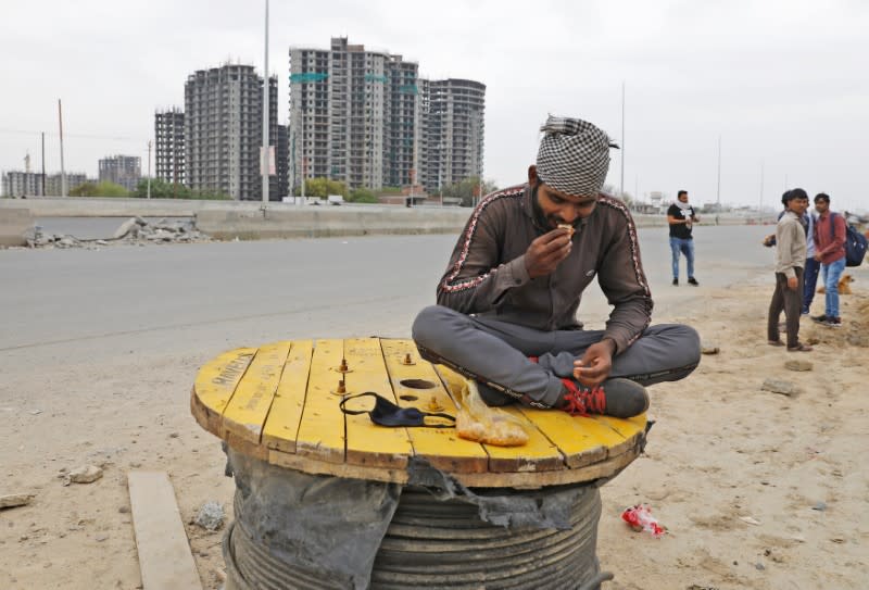 A migrant worker eats food offered by the local residents on a highway as he and others are returning to their villages, after India ordered a 21-day nationwide lockdown to limit the spreading of coronavirus disease (COVID-19), in Ghaziabad