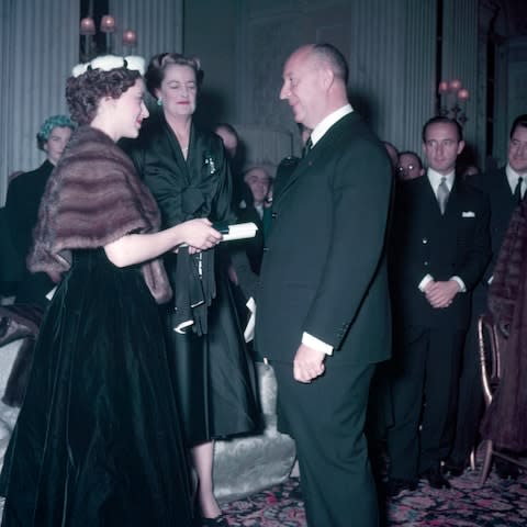 Princess Margaret presents Christian Dior with a scroll entitling him to Honorary Life Membership of the British Red Cross after the presentation of his winter collection at Blenheim Palace on 3rd November 1954.  - Credit: Popperfoto/Getty. 