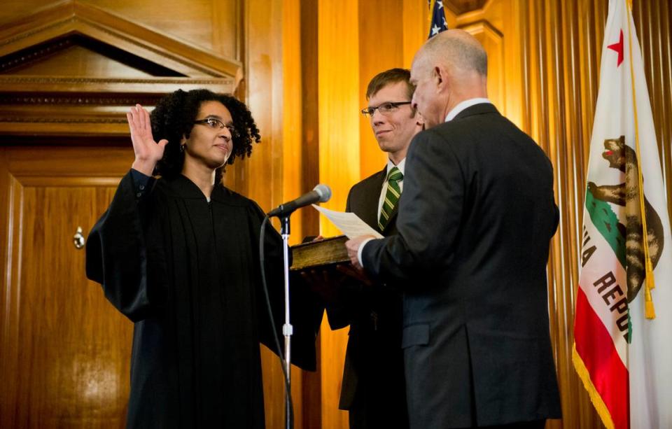 Leondra Kruger is sworn in by Gov. Jerry Brown, right, as a California Supreme Court Justice while her husband, Brian Hauck, holds the bible at the Stanley Mosk Library and Courts Building in 2015 in Sacramento.