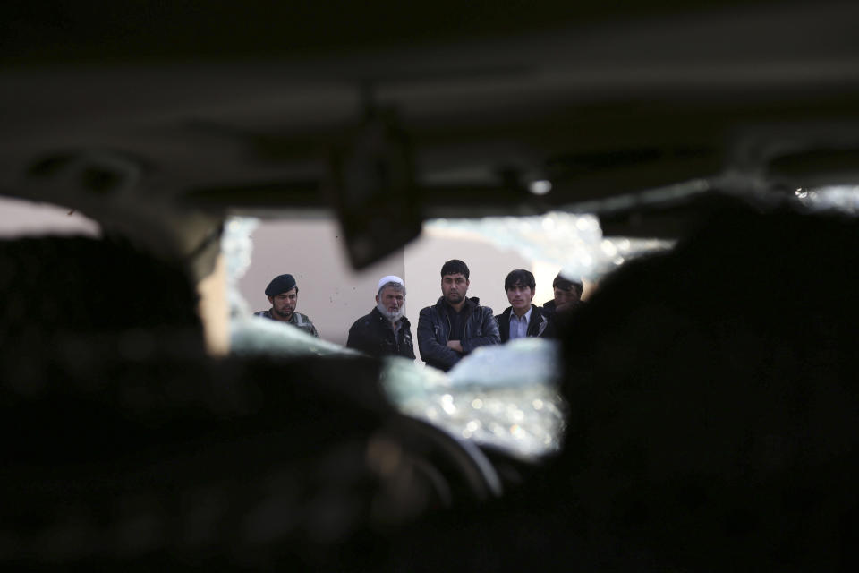 Afghan civilians watch a damaged vehicle following the Friday's suicide attack and shooting in Kabul, Afghanistan, Saturday, Jan. 18, 2014. A suicide bomber blew himself up outside a Kabul restaurant filled with foreigners and affluent Afghans, while two gunmen snuck in through the back door and opened fire Friday in a brazen dinnertime attack that killed 16 people, officials said. (AP Photo/Rahmat Gul)