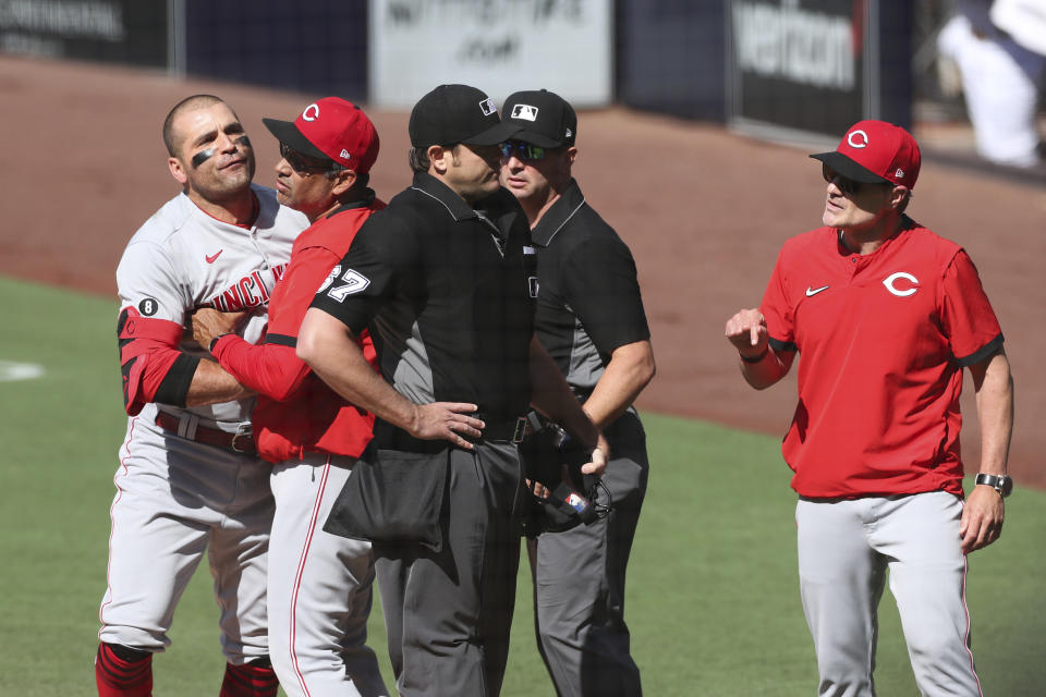 Cincinnati Reds' Joey Votto, left, is held back by bench coach Freddie Benavides as manager David Bell, right, argues with umpire Ryan Additon (67) in the first inning of a baseball game against the San Diego Padres, Saturday, June 19, 2021, in San Diego. (AP Photo/Derrick Tuskan)