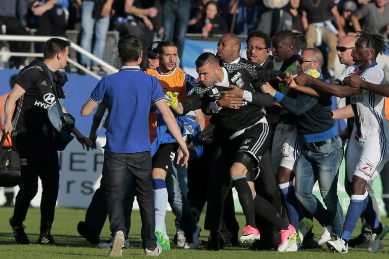 A security staff holds Lyon's goalkeeper Anthony Lopes (C) during scuffles at half-time between some of Lyon's players and Bastia supporters who invaded the pitch, during the French L1 football match Bastia vs Lyon on April 16, 2017