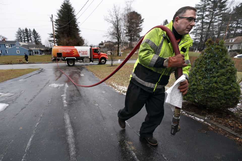 Daniel DiDonato, a deliveryman for Heatable, brings heating oil to a home in Lewiston, Maine, Thursday, Dec. 16, 2021. The amount of aid available to residents of cold weather states for heating costs has increased, but it's unlikely to plug the gap caused by higher energy costs. President Joe Biden's push for more could fall prey to partisan politics. (AP Photo/Robert F. Bukaty)